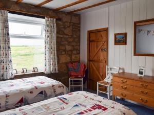 a bedroom with two beds and a dresser and a window at Sea Breeze Cottage in Staithes