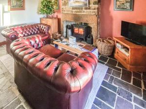 a leather couch in a living room with a fireplace at Sea Breeze Cottage in Staithes