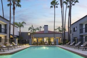 een zwembad met stoelen en een gebouw met palmbomen bij Courtyard by Marriott Los Angeles Hacienda Heights Orange County in Hacienda Heights