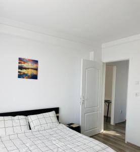 a white bedroom with a bed and a picture on the wall at City Center Apartments - Piața Unirii in Iaşi
