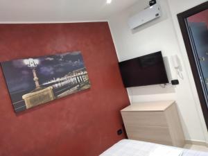 a bedroom with a red wall with a flat screen tv at B&B Romeo in Bari