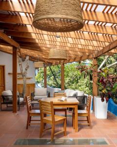 un patio con pérgola de madera, mesa de madera y sillas en Blu Galapagos Sustainable Waterfront Lodge, en Puerto Ayora
