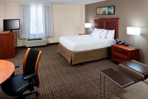 a hotel room with a bed and a desk and chair at TownePlace Suites Suffolk Chesapeake in Suffolk