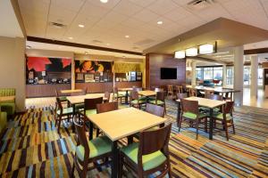 a dining room with tables and chairs and a tv at Fairfield Inn & Suites by Marriott Raleigh Capital Blvd./I-540 in Raleigh