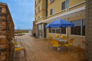 eine Terrasse mit einem Tisch und Stühlen mit einem blauen Sonnenschirm in der Unterkunft Fairfield Inn & Suites by Marriott St. Louis Pontoon Beach/Granite City, IL in Collinsville