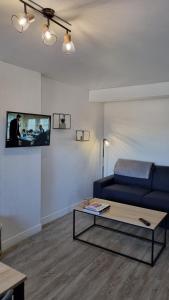a living room with a blue couch and a table at L'Honna Flow, appartement de charme près du centre. in Honfleur