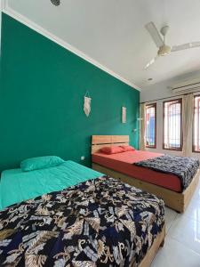 twee bedden in een slaapkamer met een groene muur bij Gorga hostel in Timuran