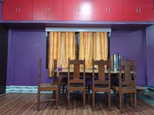 mesa de comedor con sillas y paredes púrpuras en Odyssey Stays Aalo, en Along