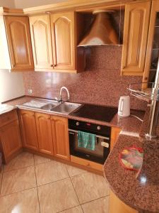 a kitchen with wooden cabinets and a sink and a stove at Apartament u Wioli in Okleśna