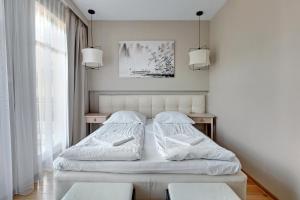 a white bedroom with two beds and two chairs at Willa Morska Deluxe by Grand Apartments in Sopot