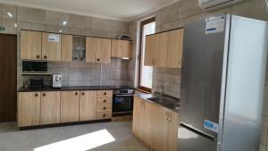 a kitchen with wooden cabinets and a stainless steel refrigerator at Pensiunea Florilor Satu Mare in Satu Mare