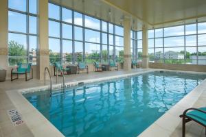 uma piscina num hotel com cadeiras azuis e janelas em Residence Inn by Marriott Arlington Ballston em Arlington