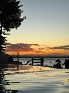 a sunset over a body of water with a pier at Hotel Portaló in Morro de São Paulo