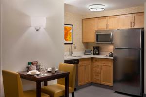 cocina con mesa y nevera de acero inoxidable en Residence Inn by Marriott Toronto Markham, en Markham