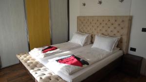 duże łóżko z białą pościelą i czerwonymi poduszkami w obiekcie Bella apartments w mieście Kruševac