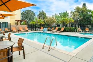 a swimming pool with chairs and tables and a table with an umbrella at Courtyard by Marriott Sacramento Cal Expo in Sacramento