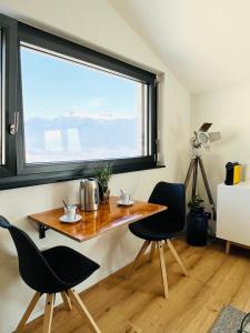 einen Tisch und Stühle in einem Zimmer mit einem großen Fenster in der Unterkunft Chambre double privative et indépendante 