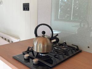 a tea kettle on a stove in a kitchen at Cosy Shepherd Huts near Newborough Forest Anglesey in Gaerwen