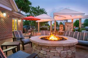 a fire pit on a patio with chairs and umbrellas at Residence Inn Frederick in Frederick