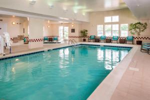 a swimming pool in a hotel with chairs and tables at Residence Inn Frederick in Frederick