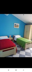 a bedroom with two beds and a blue wall at Casa Vacanza via Annarita Sidoti in Porto San Giorgio