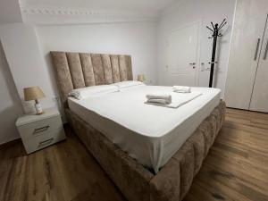 a large bed in a white room with a night stand at House Elbasan city center 3 in Elbasan