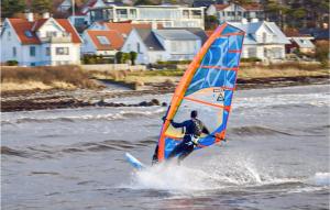 um homem está a fazer windsurf na água com casas em 1 Bedroom Pet Friendly Apartment In Helsingborg em Helsingborg