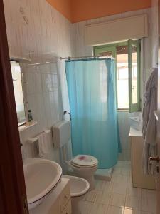 a bathroom with a toilet and a blue shower curtain at Le case di Priscilla in Donnalucata