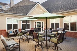 un patio con mesas, sillas y sombrillas en Residence Inn by Marriott Whitby en Whitby