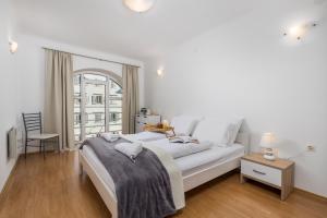 a white bedroom with a large bed and a window at Main View Apartment in Rijeka