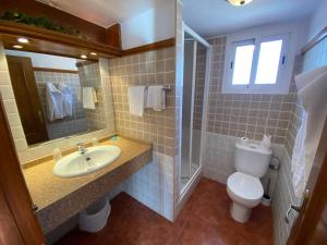 a bathroom with a sink and a toilet and a mirror at Hotel Simón in Mojácar