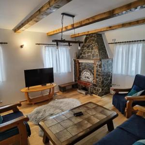 a living room with a stone fireplace and a tv at Rustic House Busteni in Buşteni