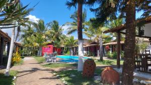 a resort with a swimming pool and palm trees at Pousada A Vila do Pirata in Prado
