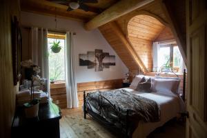a bedroom with a bed in a room with an attic at Hébergement "La Maison en Bois Rond" in Sainte-Marie