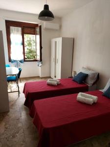 two beds in a room with red sheets at Sa Perda Bianca 8 in Cagliari