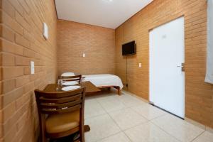 a room with a bed and a table and a door at Flats Oliveira in Pirenópolis