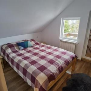 a bedroom with a bed with a plaid blanket at Rustic House Busteni in Buşteni