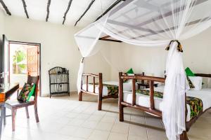 a bedroom with two beds and a table at Zarafa House in Diani Beach