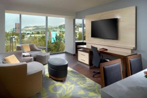 een woonkamer met een tv, een bank en een bureau bij Courtyard by Marriott Queretaro in Querétaro