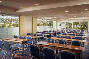 una sala de conferencias con mesas, sillas y ventanas en Courtyard by Marriott Queretaro en Querétaro