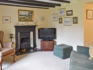 a living room with a fireplace and a tv at The Cottage in Sinnington