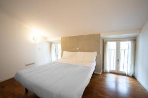 een groot wit bed in een kamer met 2 ramen bij Apartment Sant'Alessandro 19 - Sostify in Bergamo