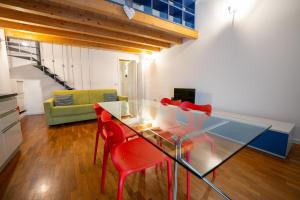 een eetkamer met een glazen tafel en rode stoelen bij Apartment Sant'Alessandro 19 - Sostify in Bergamo