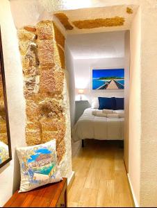 een slaapkamer met een bed en een stenen muur bij Carbonari Holiday House in Cefalù