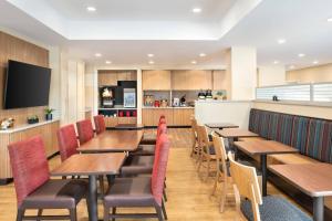 a restaurant with wooden tables and chairs and a kitchen at TownePlace Suites by Marriott Milwaukee Grafton in Grafton