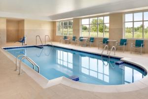 a large pool in a hotel with chairs and tables at TownePlace Suites by Marriott Milwaukee Grafton in Grafton