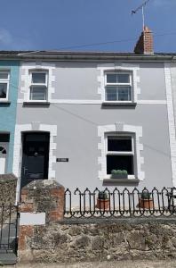 a white house with a fence in front of it at Seasalt Cottage - Modernised traditional cottage, Sleeps 5,short walk to beaches, town, amenities in Pembrokeshire