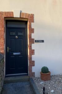 une porte noire sur le côté d'un bâtiment dans l'établissement Seasalt Cottage - Modernised traditional cottage, Sleeps 5,short walk to beaches, town, amenities, à Pembrokeshire