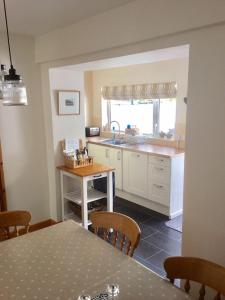 une cuisine avec des placards blancs et une table avec des chaises dans l'établissement Seasalt Cottage - Modernised traditional cottage, Sleeps 5,short walk to beaches, town, amenities, à Pembrokeshire