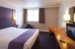 a hotel room with a bed and a television at Premier Inn Manchester Airport Runger Lane North in Hale